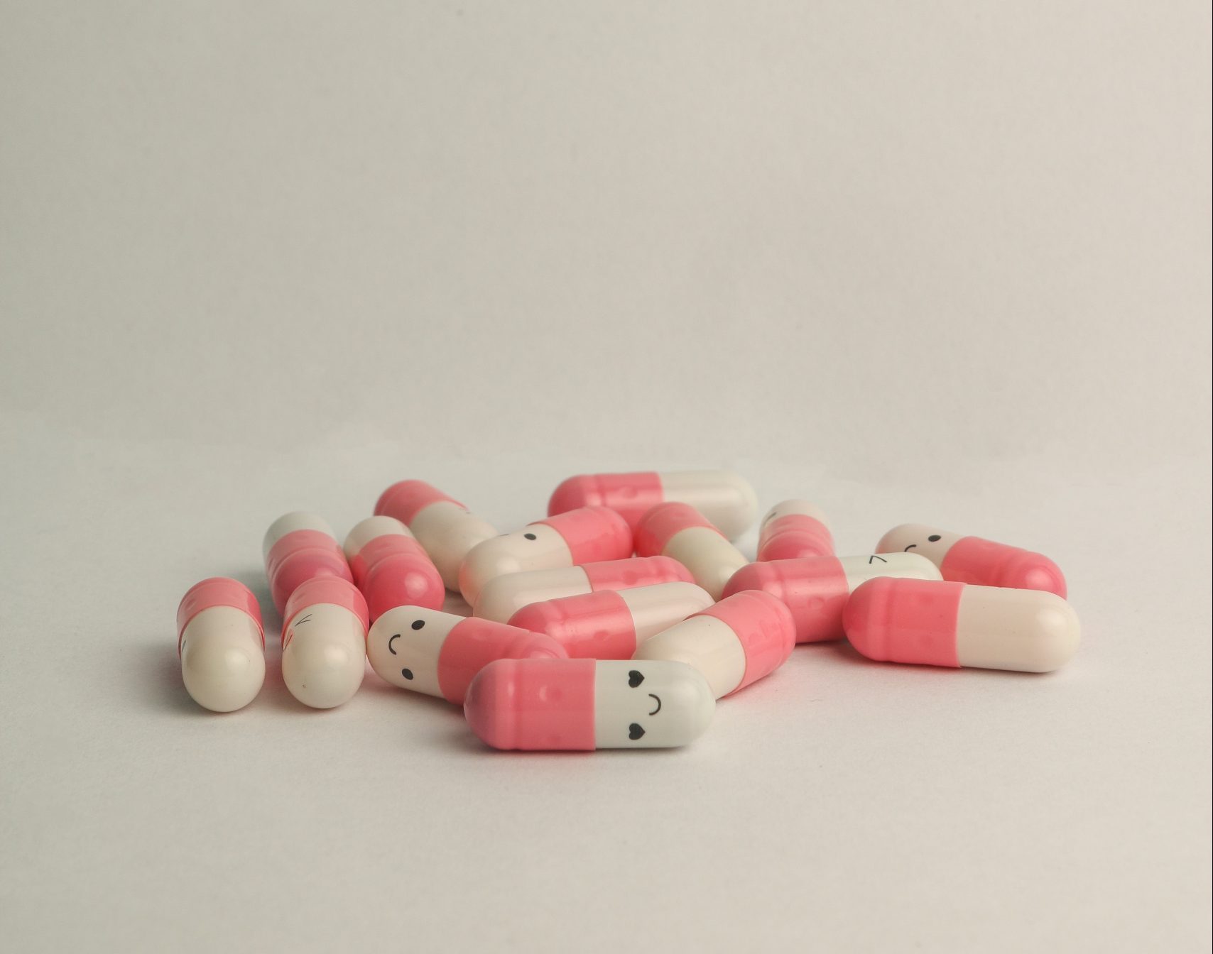 White and pink pills with smiley face on white end to depict antidepressants
