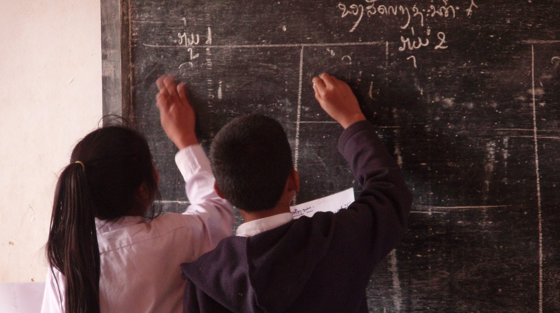 Two students writing at a blackboard