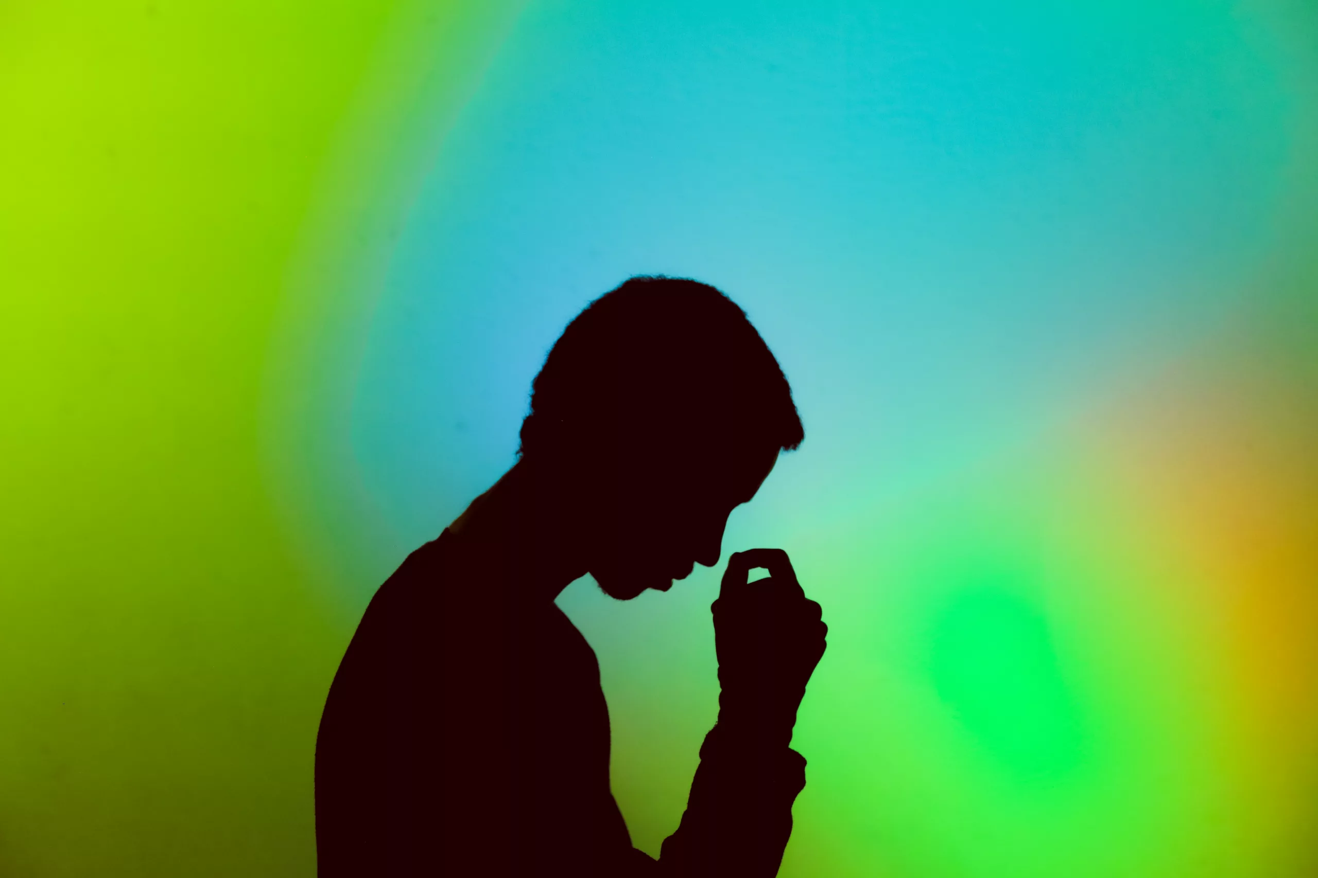 A man in thought against a multi-coloured background