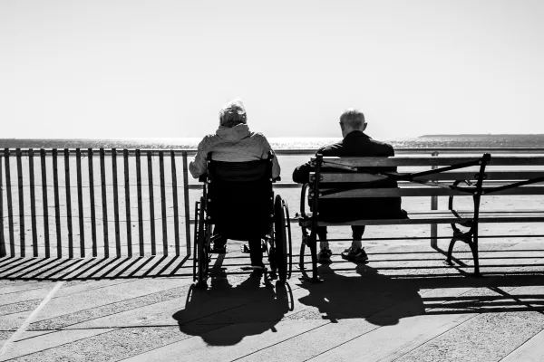 Elderly couple sitting on bench overlooking sea