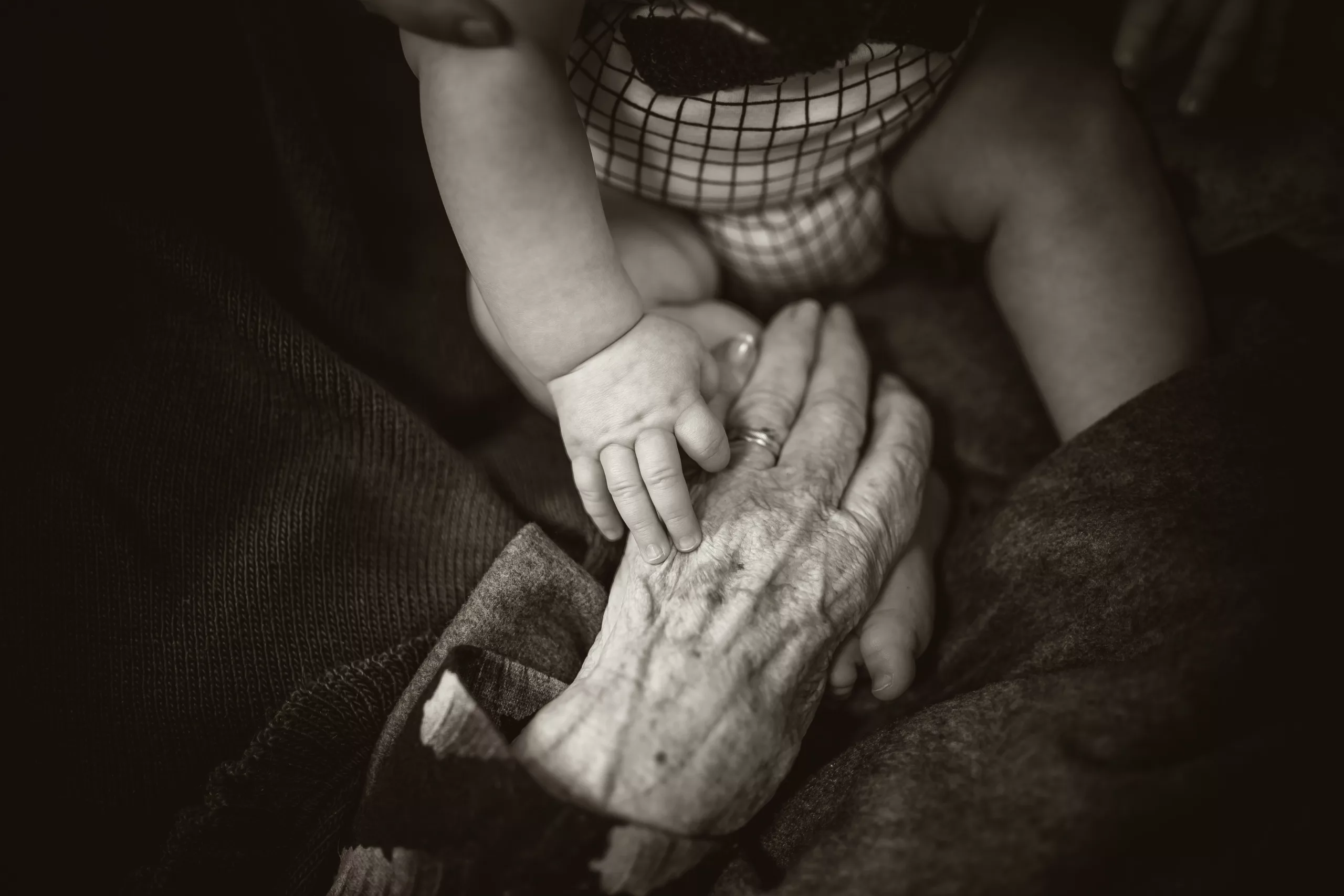 A baby holding an old grandma's hand