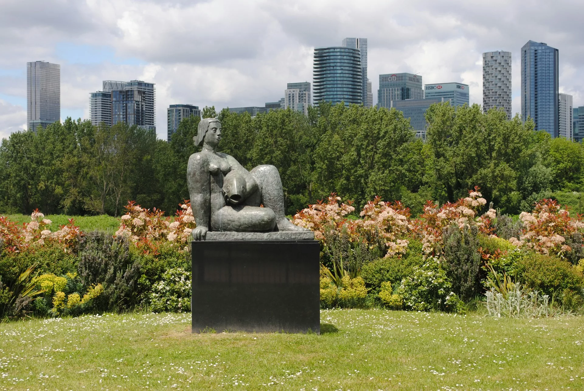 Sculpture of a woman in a park with skyscrapers