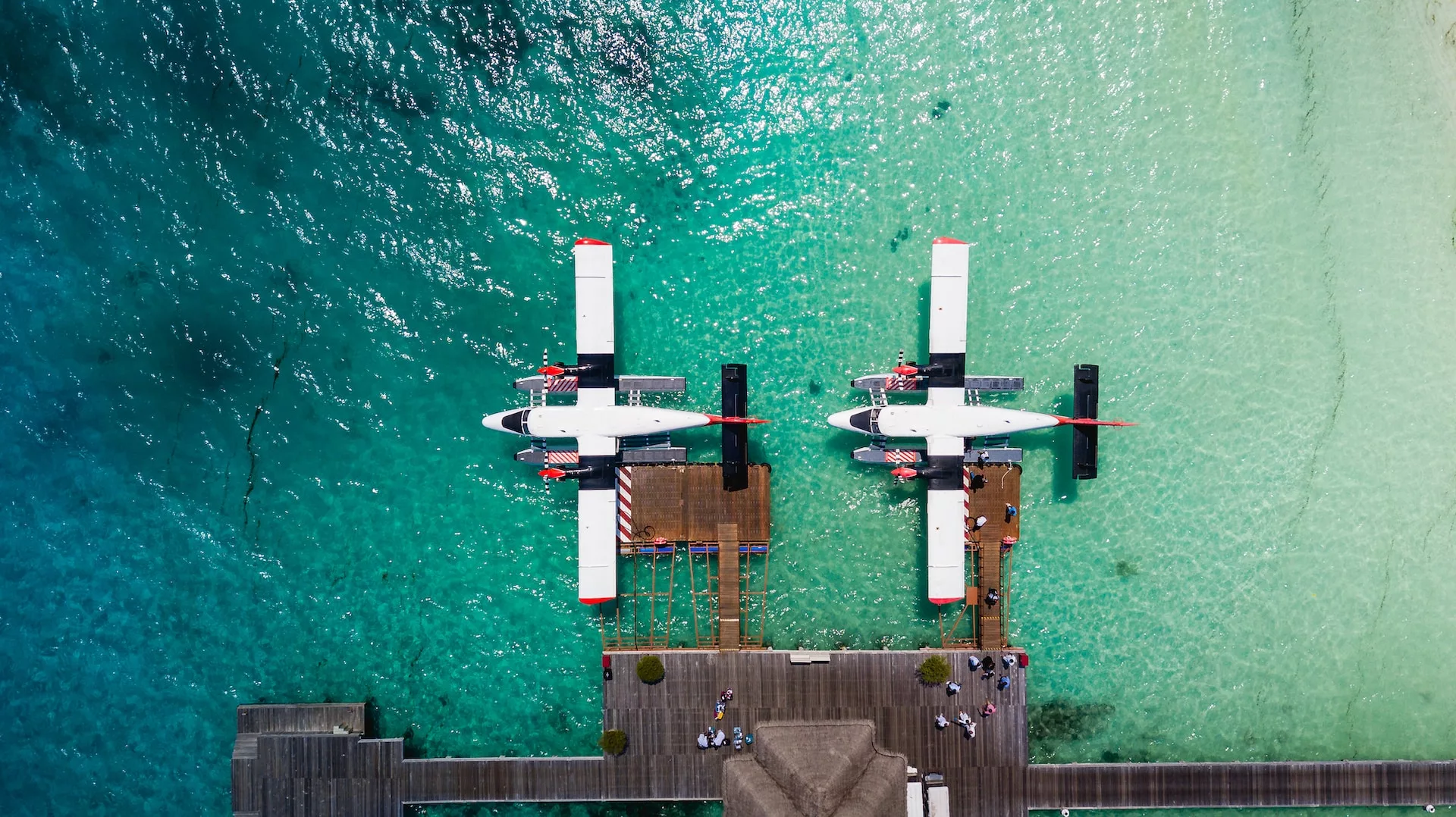 Two identical twin water-landing jets docked by the ocean.