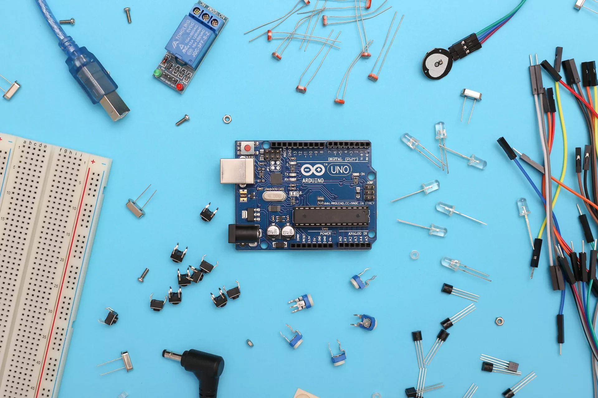 A blue background with a series of scattered electronic parts.
