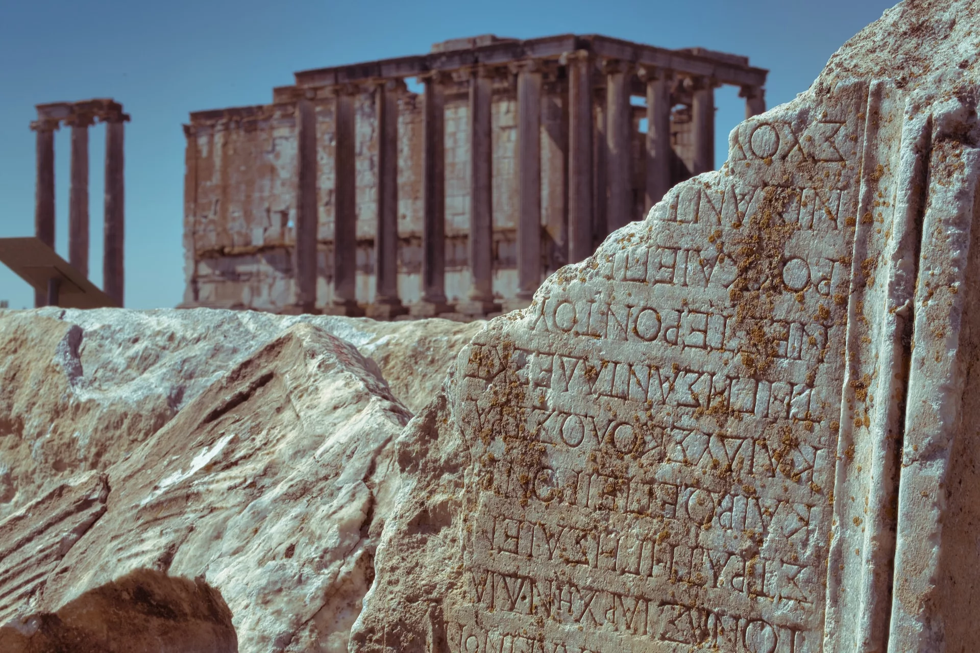 stone with ancient greek inscriptions in front of a sculpture