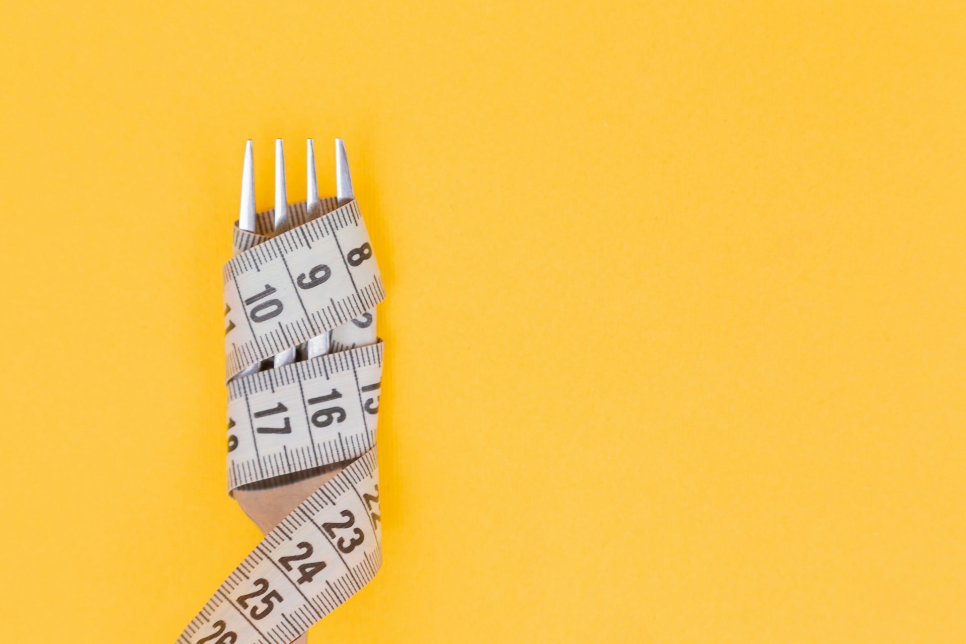 A picture of a fork wrapped in a tape measure