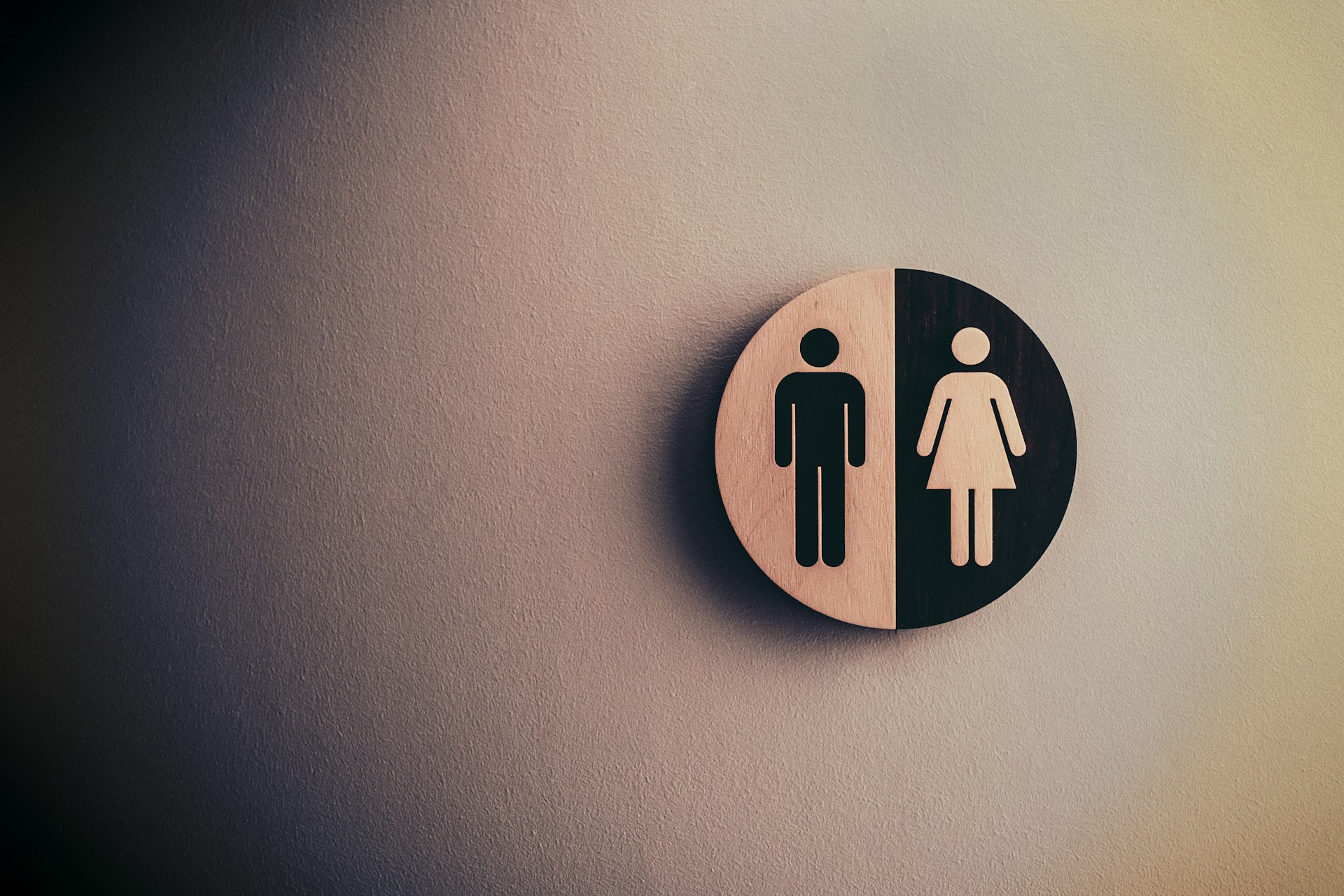 A badge split in half, with the left depicting a male and the right depicting a female.