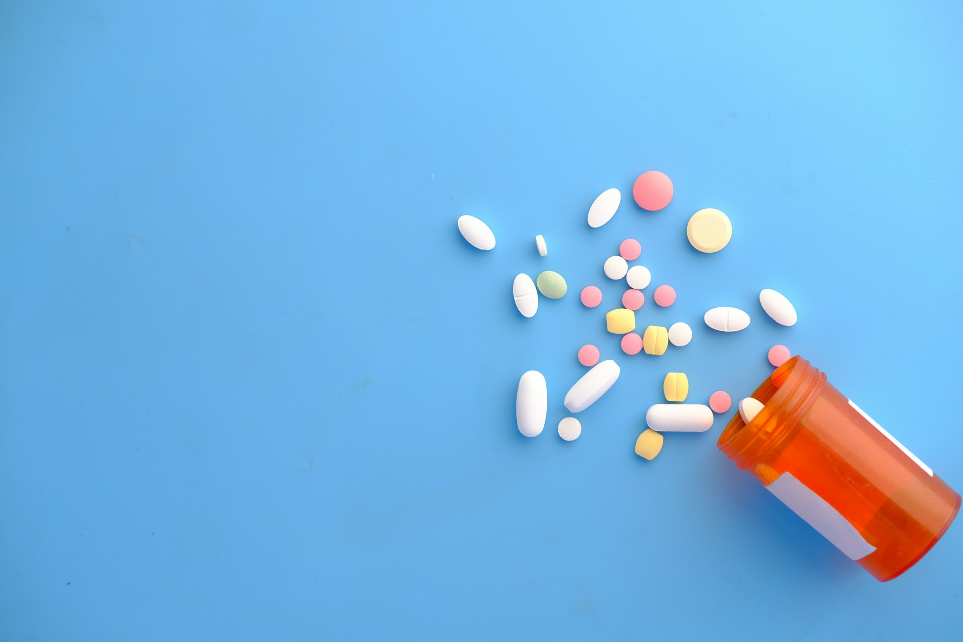 Various pills spilling out of a container