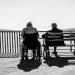 Elderly couple sitting on bench overlooking sea